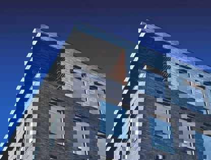 Modern gebouw met een metalen dak en een bakstenen gevel, tegen een achtergrond van een blauwe lucht.