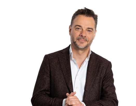 Sander Vis in een donkerbruin jasje en wit overhemd, staand met de handen in elkaar gevouwen, op een zwarte achtergrond.