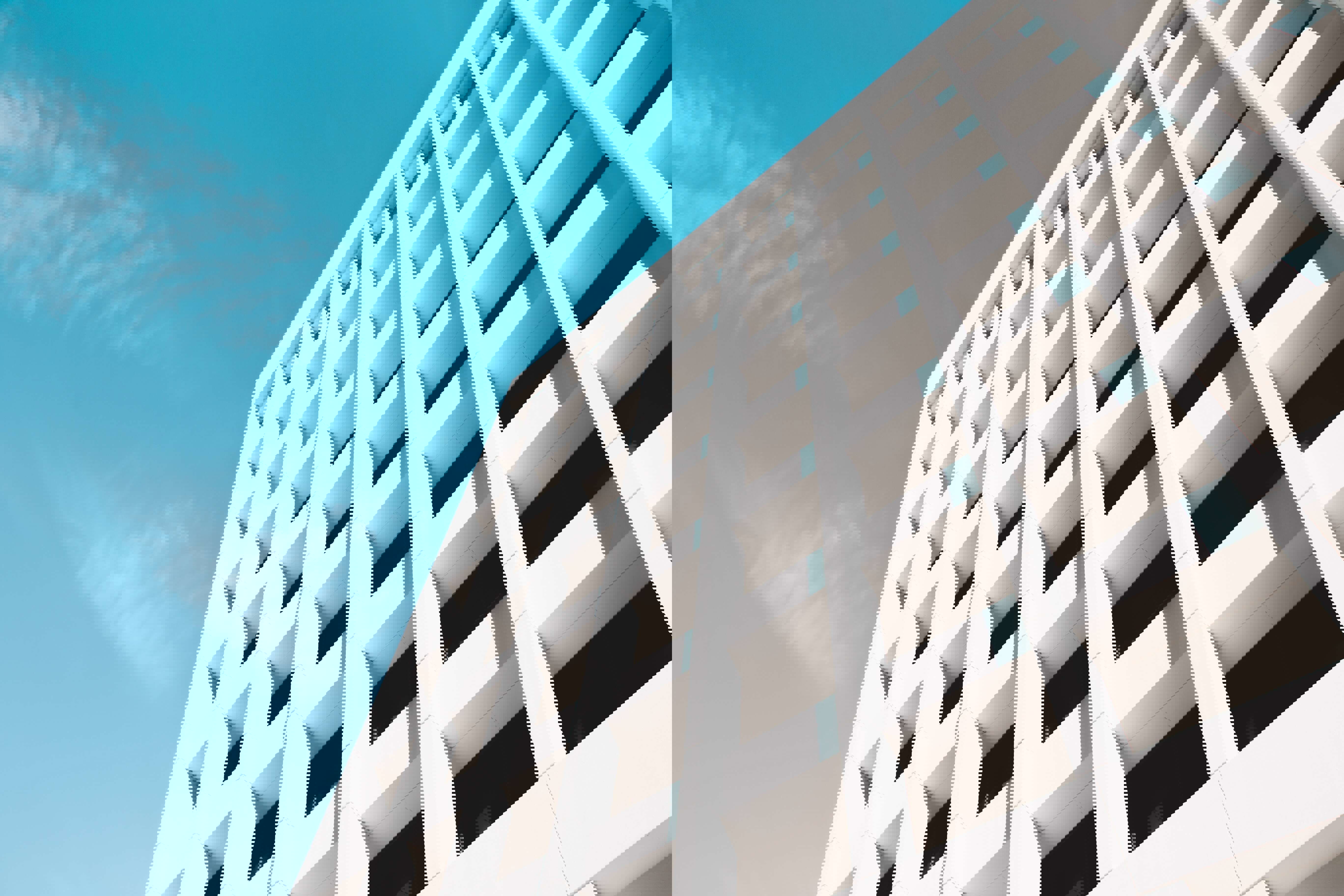 Moderne witte gevel van een gebouw met opvallende rechthoekige vensters onder een heldere blauwe lucht.