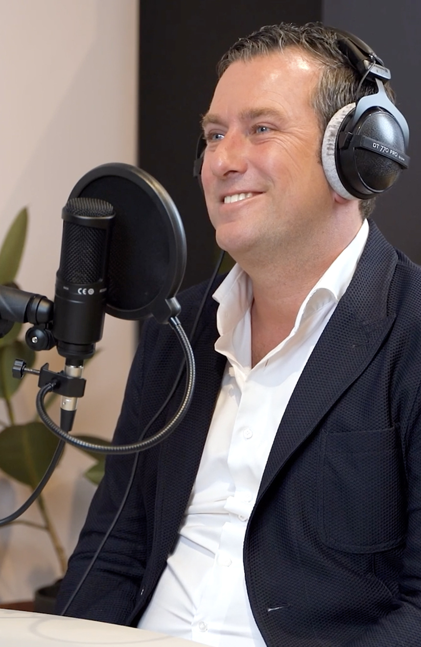 Wouterlangeveld met een microfoon en koptelefoon in een studio, die zich voorbereidt op een opname.