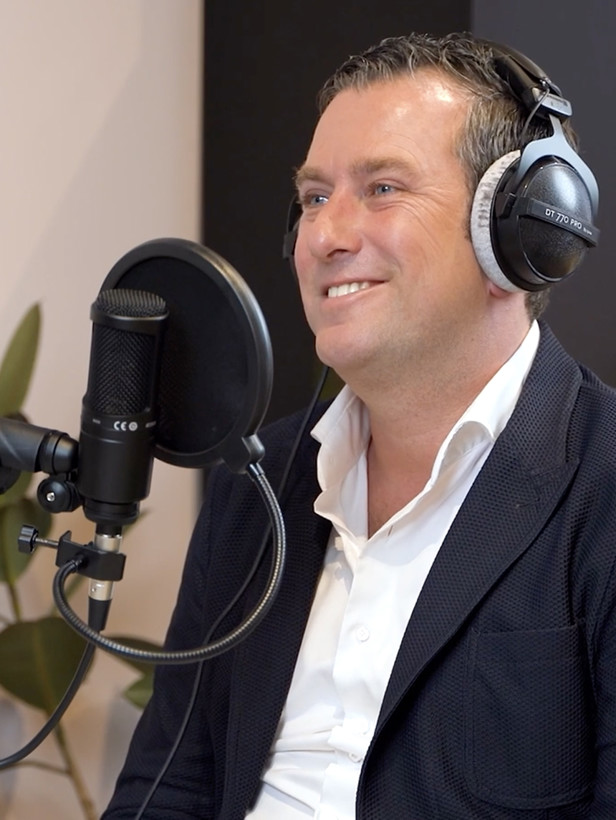 Wouterlangeveld met een microfoon en koptelefoon in een studio, die zich voorbereidt op een opname.